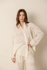 Camisa de manga larga color crema, confeccionada en algodón con bordados florales. Presenta cuello clásico, cierre frontal con botones y corte holgado.