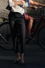 Pantalón negro tobillero de tiro medio con cintura elástica en la espalda, bolsillos delanteros y falsos bolsillos de vivo en la espalda. Bajo con aberturas laterales. Cierre frontal con cremallera, botón interior y gancho.