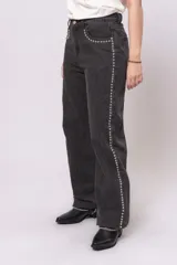 Pantalón de jean negro de corte recto con tachas plateadas en los bolsillos y a lo largo de las costuras laterales.