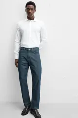 Camisa blanca de algodón, corte regular, con cuello italiano abierto, manga larga con puños abotonados y cierre frontal con botones.