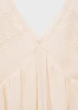 Vestido corto color crema con breteles finos y escote en V con encaje.