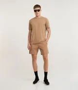 Remera deportiva de hombre, color amarillo mostaza, de manga corta y cuello redondo. Presenta un pequeño logo circular bordado en el pecho.