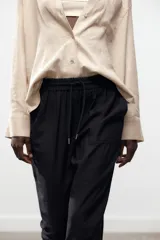 Pantalón jogger marrón de tiro alto con cintura elástica ajustable con cordones, bolsillos delanteros y puños elásticos en los tobillos.