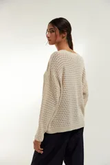 Sweater de punto calado color crudo, con escote en V y mangas largas.