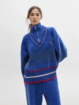 Sweater azul con cuello alto con medio cierre, textura tipo terciopelo y puños acanalados.