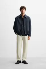 Pantalón chino color beige, corte recto, con bolsillos laterales y traseros. Cierre frontal con cremallera y botón.