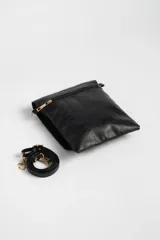 Bandolera negra de cuero sintético con correa larga regulable y cierre con solapa.
