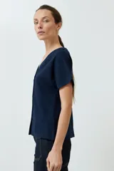 Remera verde oliva con escote en V, manga corta con dobladillo y cierre frontal con botones.