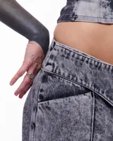 Pantalón de denim gris con lavado artesanal, corte sastrero de pierna ancha, tiro alto y pretina cruzada.