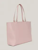 Bolso tipo tote color rosa pálido, con doble asa de hombro y cierre superior con cremallera. Incluye un dije colgante con el logo de la marca y el logo metálico en la parte frontal.