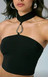 Top negro tipo bandeau, ajustado al cuerpo, con cuello tipo choker incorporado que se une al centro del busto mediante una argolla metálica plateada.