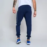 Pantalón de jogging azul marino con puños ajustados, cintura elástica con cordón y bolsillos laterales. Presenta el escudo del Club Nacional de Football y el logo de Umbro.