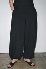 Pantalón de tiro medio confeccionado en hilatura con mezcla de viscosa, color negro. Presenta bolsillos laterales ocultos en costura, bajo acabado en puño con botones y cierre frontal con cremallera, botón y ganchos metálicos.