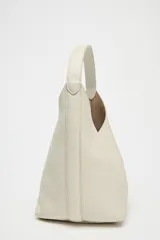 Bolso tipo saca de cuero color gris claro con textura granulada. Tiene asa de hombro y cierre con imán. Incluye cartera interior extraíble con bolsillo.