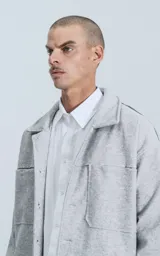 Chaqueta gris melange de paño con cuello clásico, cierre frontal con botones negros, dos bolsillos de parche en el pecho y dos bolsillos laterales.