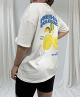 Remerón blanco de corte holgado con estampado de limones y texto en azul.