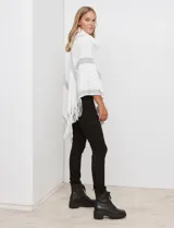 Poncho tejido Barrington color blanco con diseño de rombos en relieve y franjas diagonales grises. Posee cuello alto de tejido afelpado (velour) blanco y terminación con flecos en el ruedo.