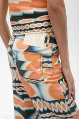 Pantalón de jean azul oscuro con corte acampanado, tiro medio y dobladillo en el ruedo. Presenta costuras marcadas en el frente y estampado abstracto en tonos grises y blancos en el interior del dobladillo.