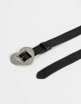 Cinturón negro de cuero sintético con hebilla de metal plateado en forma de corazón con incrustaciones de strass.