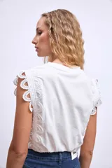 Remera blanca de algodón con mangas cortas y detalle de encaje calado en los hombros.