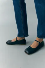 Ballerinas negras de cuero sintético con punta redondeada y tira con hebilla sobre el empeine.