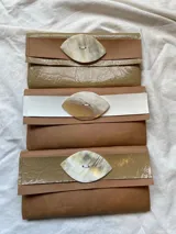 Billetera tipo sobre de ecocuero color beige con textura craquelada y solapa con aplique de cuero liso y botón de guampa.