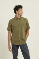 Camisa sport de manga corta color verde oliva, línea premium, con cuello clásico, cierre frontal con botones de coco y bolsillo de parche en el pecho. Confeccionada en lino y algodón.