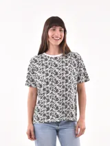 Remera blanca con estampado de hojas y flores en negro.