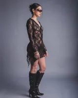 Vestido de encaje negro con corte irregular, escote en V y mangas campana.