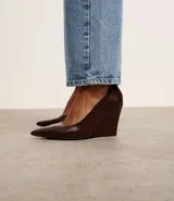 Zapato de tacón tipo anabela color marrón oscuro, con punta fina y confeccionado en material sintético.