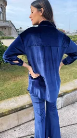 Camisa azul de terciopelo, corte oversize, con cuello camisero, manga larga y cierre frontal con botones.