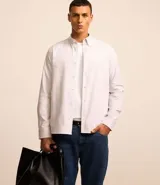 Camisa de manga larga confeccionada en algodón blanco. Presenta cuello camisero abotonado y botonadura frontal.