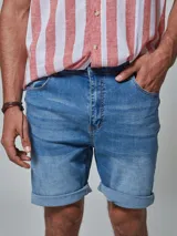 Bermuda de jean de lavado medio con ruedo de color, dos bolsillos laterales, dos en la parte posterior y uno cerillero. Cierre frontal y botón.