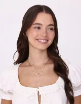 Collar corto dorado con doble cadena, una de eslabones y otra con cuentas y perlas. Incluye dijes de corazones y flores encapsuladas.