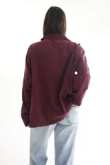 Camisa oversize color borgoña de pana con cuello camisero, cierre frontal con botones, dos bolsillos con solapa en el pecho y mangas largas con puños abotonados.