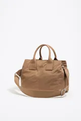 Bolso bandolera color crudo con doble asa de mano y correa bandolera ajustable y extraíble. Tiene dos bolsillos frontales con cierre y logo de la marca en el frente.