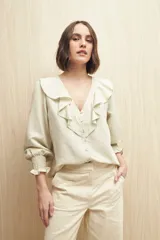 Camisa color crema a rayas verticales finas, con escote en V, volados en el frente y mangas 3/4 con puños elastizados.