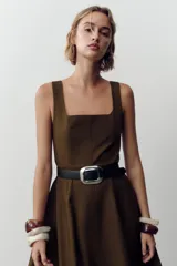 Vestido marrón midi de escote cuadrado y tirantes anchos, con cinturón negro y falda evasé. Cierre trasero con cremallera oculta.
