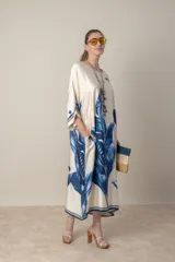 Vestido italiano tipo túnica en satén color natural con estampado de hojas de palma en tonos azules. Tiene corte suelto, mangas tres cuartos y bolsillos laterales.
