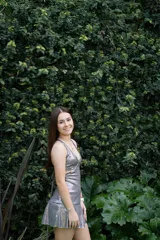 Vestido corto de lentejuelas color verde oliva, con escote en V, breteles finos cruzados en la espalda, cut-outs laterales y volado en el ruedo.