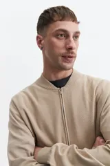 Campera tejida de punto color beige, con cuello rib, puños y bolsillos laterales.