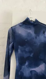 Vestido corto de microtul con estampado abstracto en tonos azules y celestes, cuello alto y mangas largas acampanadas.