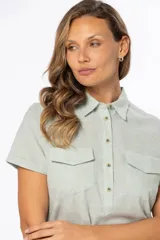 Camisa color salmón de lino, de corte clásico, con cuello camisero, manga corta, cierre frontal con botones y dos bolsillos de parche en el pecho.