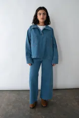 Camisa celeste de denim con cuello clásico, mangas largas con puños abotonados, cierre frontal con botones a presión y dos bolsillos de parche en el pecho.