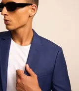 Saco de traje azul cobalto, modelo social, con cuello solapa, abotonado delantero, bolsillos y mangas largas.