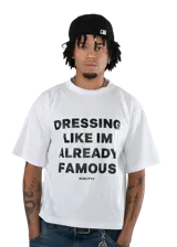 Remera blanca de algodón con corte híbrido entre regular y boxy. Estampa frontal con la frase "DRESSING LIKE IM ALREADY FAMOUS" y el logo de la marca KUALITY® en color negro.