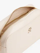 Bandolera Tommy Hilfiger color crema con monograma TH en relieve. Tiene correa ancha ajustable y extraíble, cierre de cremallera, bolsillo interior con cremallera y monedero extraíble con cremallera.