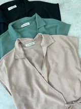 Blusa color beige con cuello camisero, corte cruzado, mangas cortas y lazo lateral.