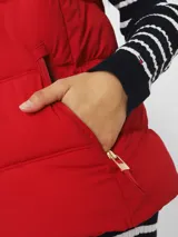 Chaleco rojo acolchado con cuello alto, cierre frontal con cremallera dorada y bolsillos laterales con cremallera dorada.