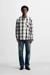 Camisa de hombre regular fit confeccionada en tejido de algodón a cuadros en tonos azul oscuro y verde oliva. Tiene cuello solapa, manga larga con puños abotonados, bolsillo de plastrón en el pecho y cierre frontal con botones.